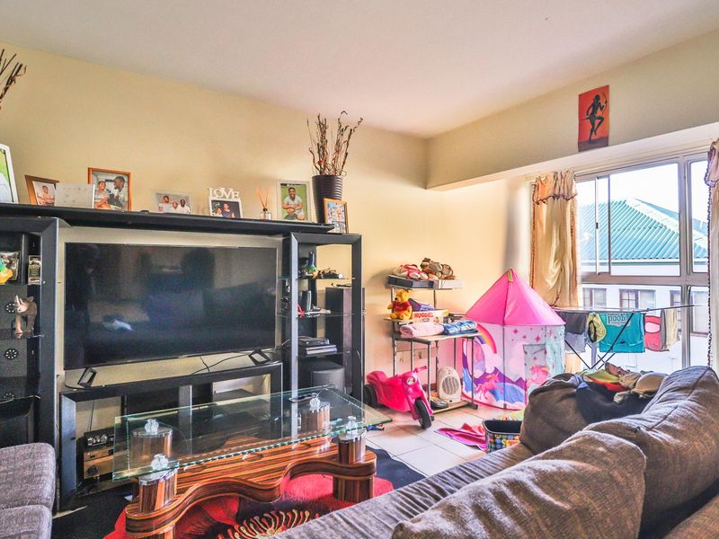 A living room area featuring tiled flooring and a large sliding window providing natural light.