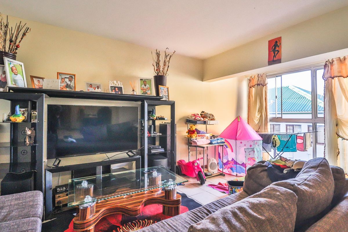 A living room area featuring tiled flooring and a large sliding window providing natural light.