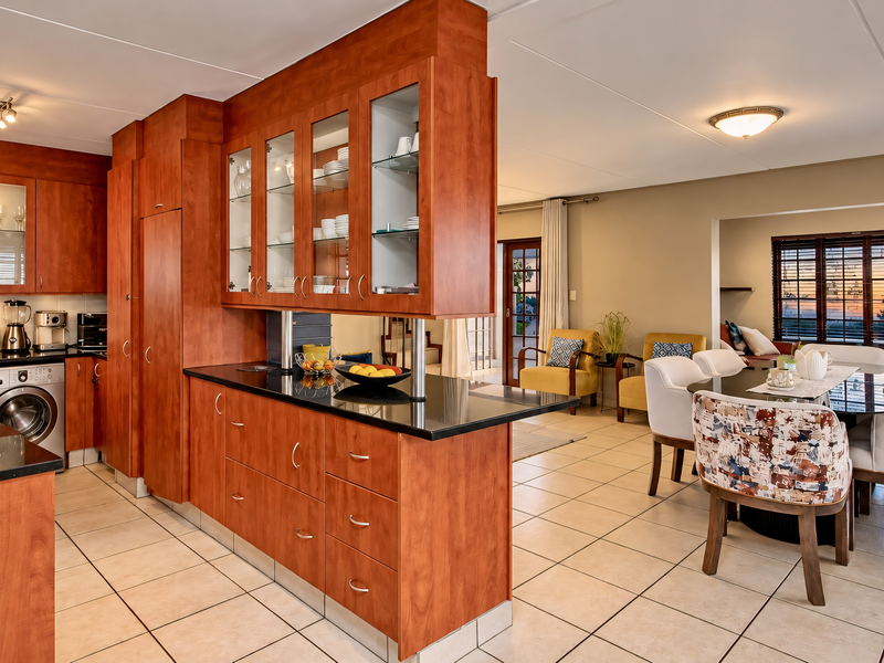 Spacious open-plan kitchen and dining area featuring cherry wood cabinetry, black granite countertops, and ceramic tile flooring, seamlessly connecting to the living space.