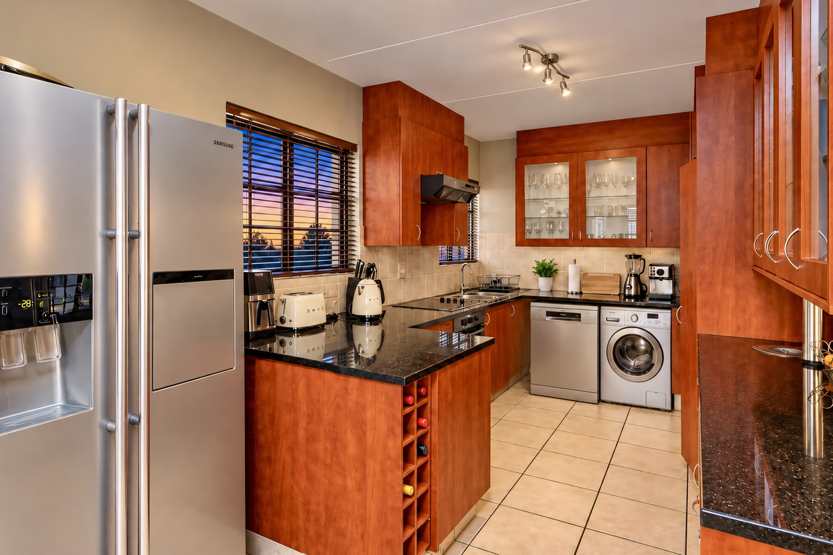 A well-appointed kitchen featuring cherry wood cabinetry, granite countertops, ceramic tile flooring, and integrated storage solutions with a functional layout.