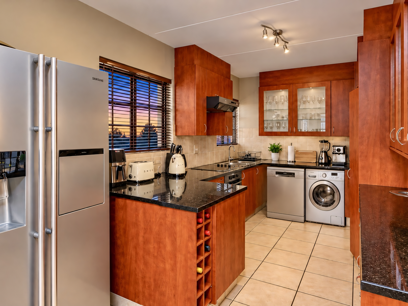 A well-appointed kitchen featuring cherry wood cabinetry, granite countertops, ceramic tile flooring, and integrated storage solutions with a functional layout.