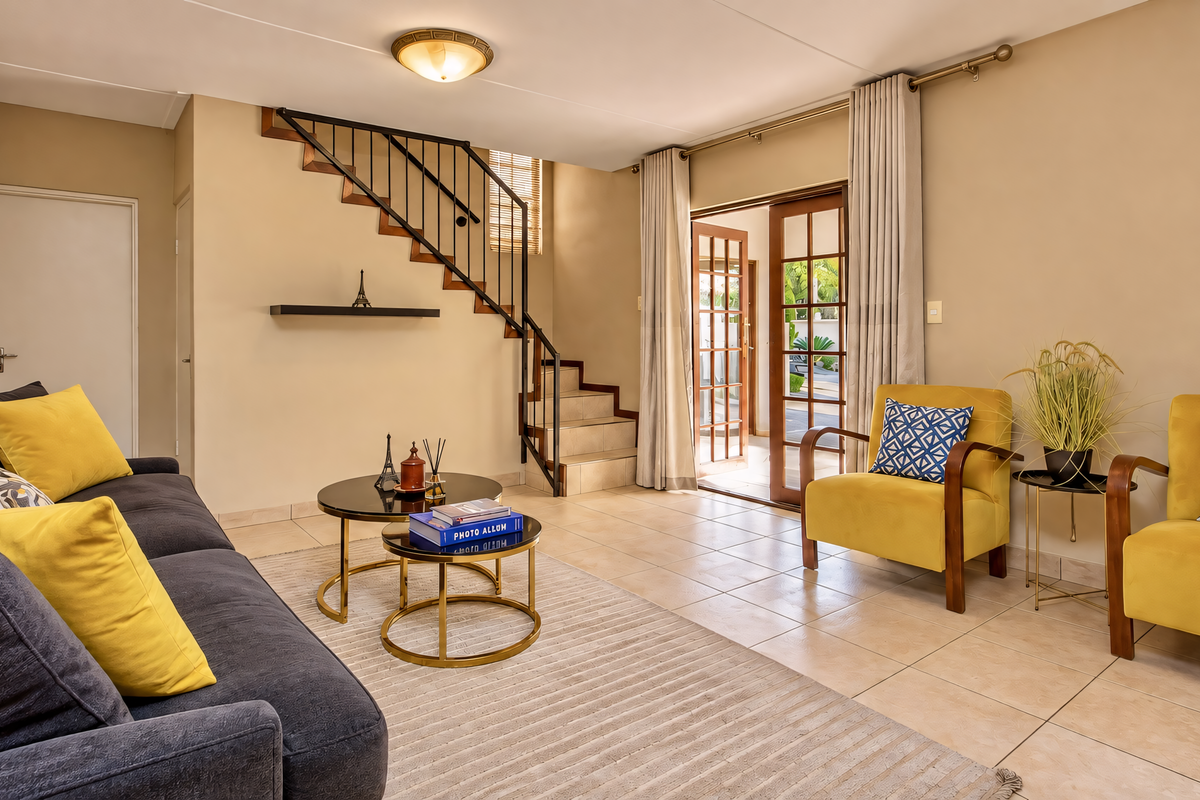 A bright living room featuring tiled flooring, a staircase with a metal railing, and sliding glass doors providing access to the outdoor area.