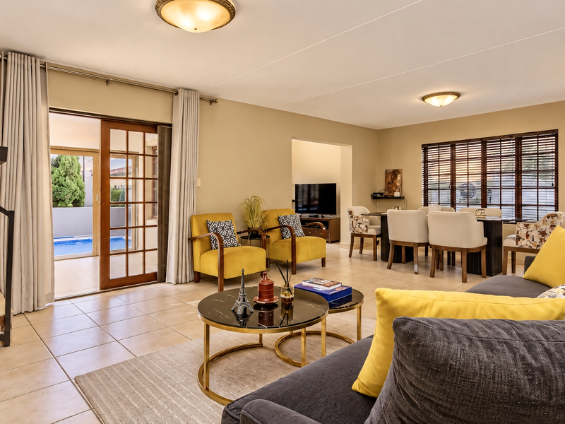 Spacious open-plan living and dining area featuring tiled floors, large sliding doors leading to the pool area, and abundant natural light.