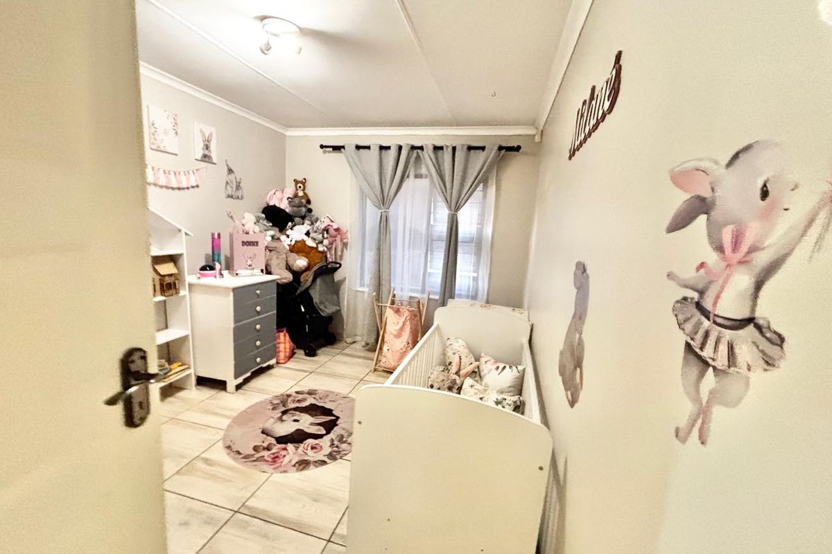 A functional bedroom featuring tiled flooring and neutral wall finishes, currently utilized as a nursery.