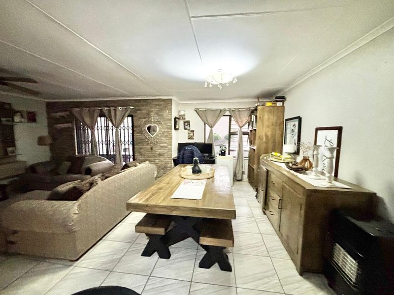 Open-plan living and dining area featuring tiled flooring and a decorative stone feature wall, providing a versatile space for family living.