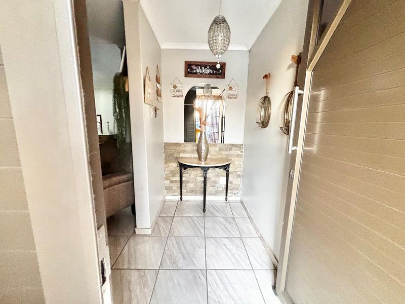 A welcoming entrance hall featuring light-toned floor tiles and a decorative stone veneer accent wall.