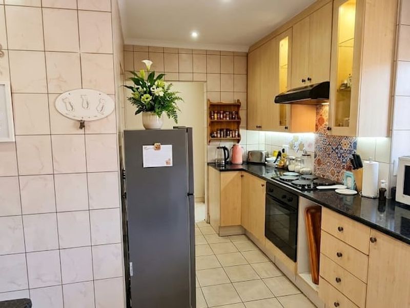 A functional kitchen featuring light wood cabinetry, granite countertops, a built-in oven, and a tiled splashback with decorative accents.