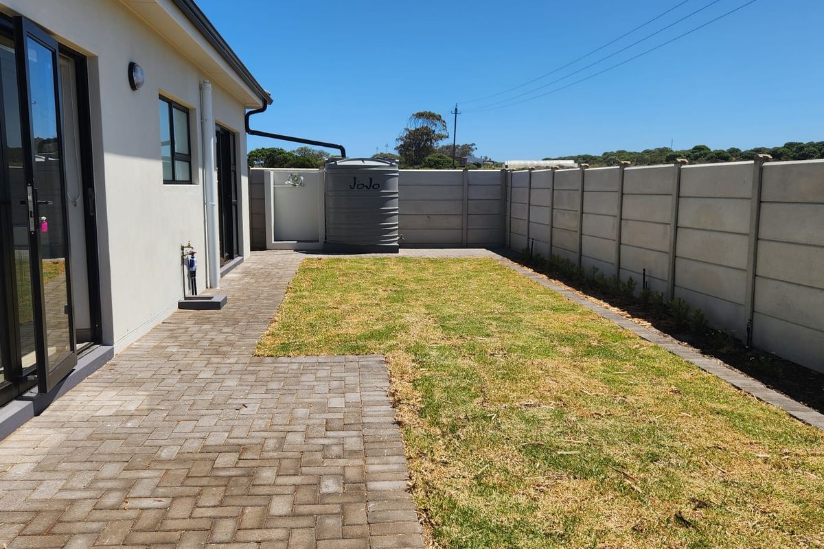 A private rear garden featuring a paved patio area, a water storage tank, and a precast concrete boundary wall.