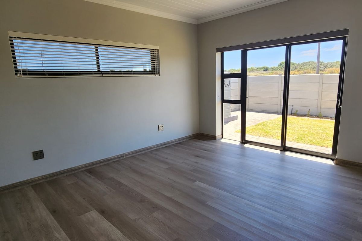 Bright and modern living area featuring laminate flooring, recessed ceiling lights, and large sliding glass doors providing direct access to the rear garden.