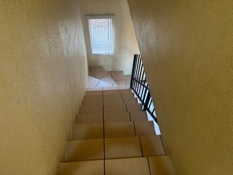 A staircase with tiled steps and a metal balustrade leading to a landing area with a window.