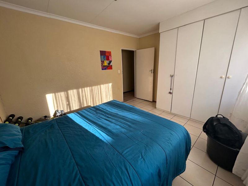 A bedroom featuring tiled flooring, coved ceilings, and built-in cupboards providing ample storage space.