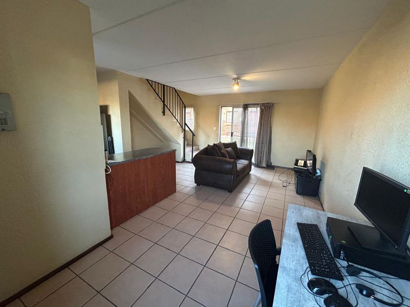Open plan living area featuring tiled flooring, a breakfast counter, and a staircase leading to the upper level with access to a patio.