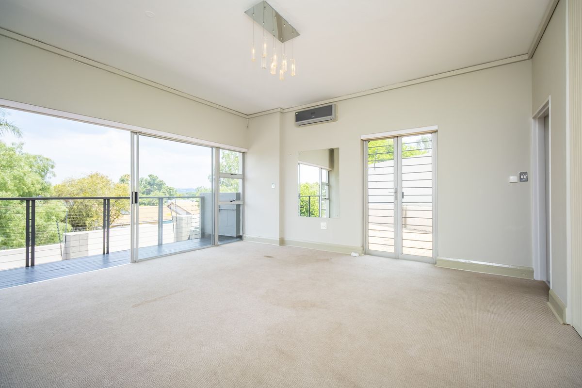 Spacious living area featuring large sliding glass doors leading to a balcony, wall-mounted air conditioning unit, and neutral finishes.