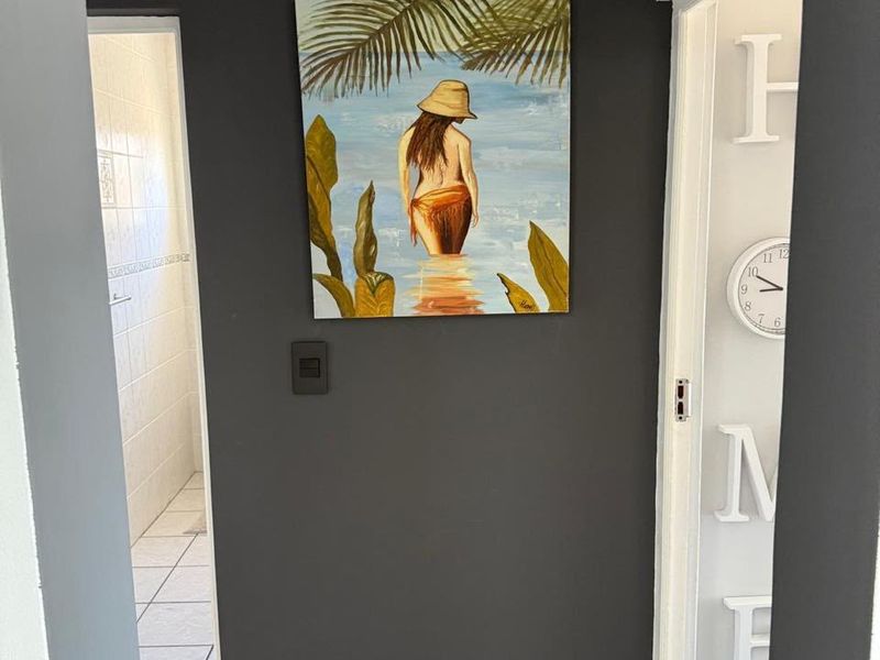 A view through a hallway showing tiled flooring and access to an adjacent bathroom area.