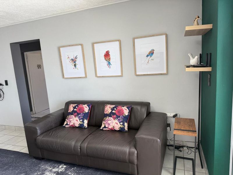 A living room area featuring tiled flooring, a textured ceiling, and built-in wall shelving against a painted accent wall.