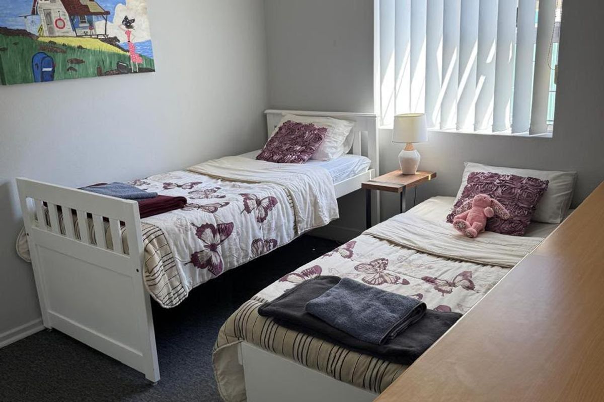 A functional bedroom featuring carpet flooring and vertical blinds, providing a neutral space ready for personalization.