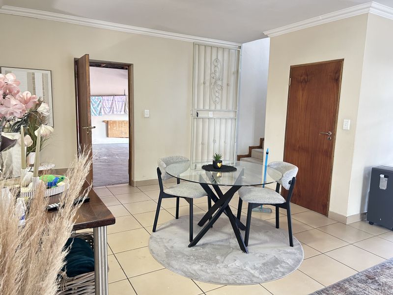 A dining area featuring tiled flooring, crown molding, and access to adjacent rooms through wooden doors and a security gate.