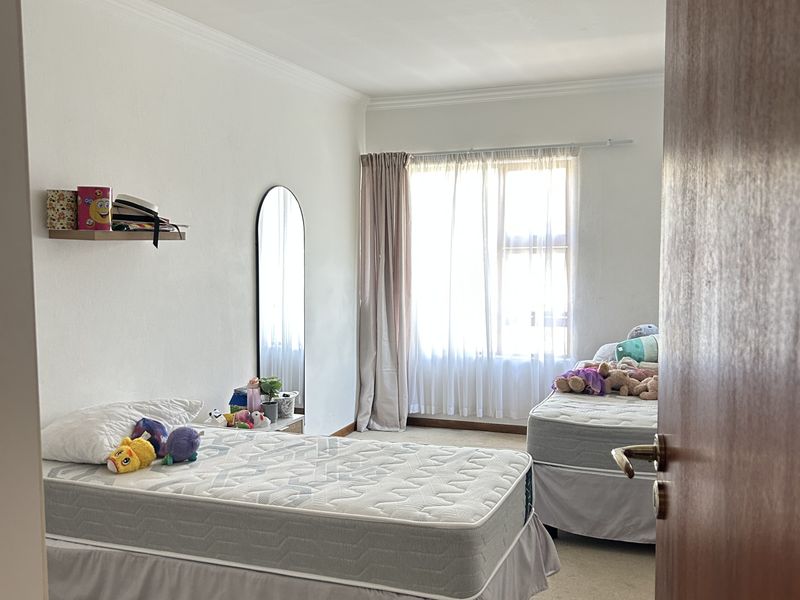 A functional bedroom featuring carpeted flooring, a central ceiling light, and a window with curtain rods, offering a neutral space ready for personalization.