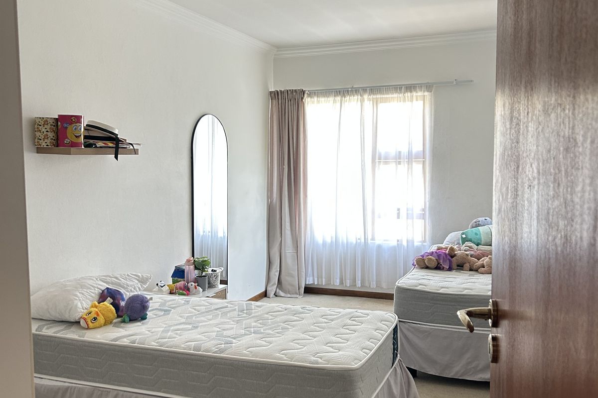 A functional bedroom featuring carpeted flooring, a central ceiling light, and a window with curtain rods, offering a neutral space ready for personalization.