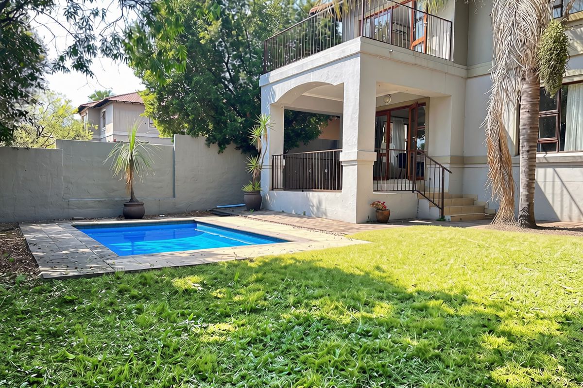 Rear exterior view of the townhouse featuring a private swimming pool, a covered patio, and an upper-level balcony with metal railings.