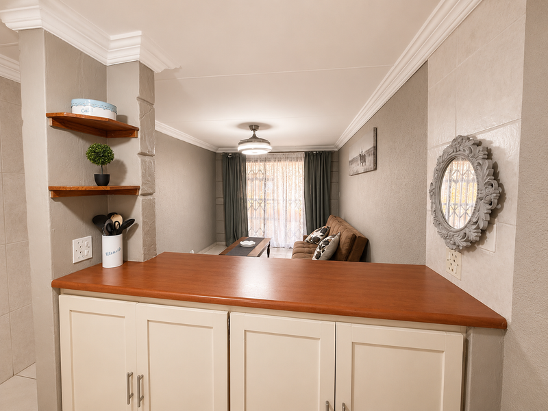 Open plan living area featuring built-in cabinetry with a wooden countertop, crown molding, and a ceiling fan, leading to a sliding glass door.