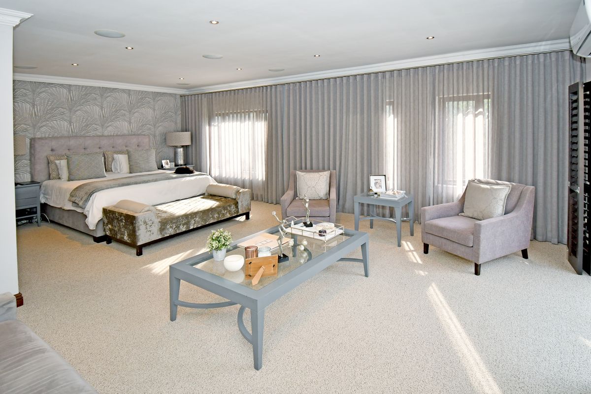 Spacious master bedroom featuring neutral carpeting, recessed lighting, and floor-to-ceiling curtains, creating a bright and well-maintained living space.