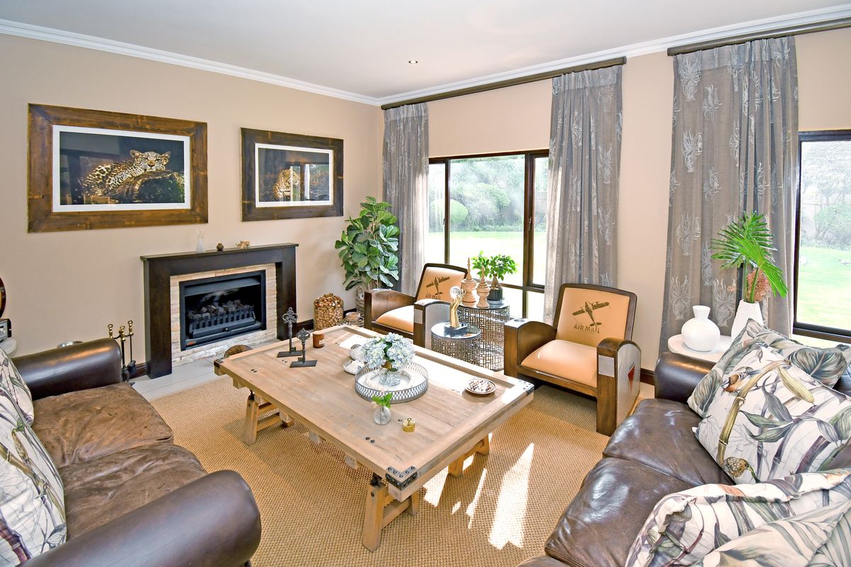 A well-maintained living room featuring a built-in fireplace, crown molding, and large sliding glass doors that provide ample natural light and garden views.