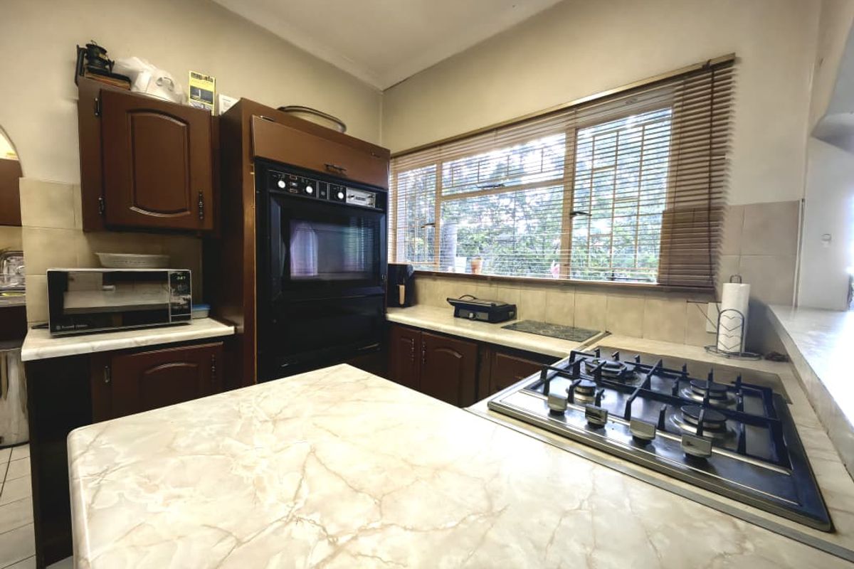 A functional kitchen featuring timber cabinetry, laminate countertops, a built-in oven, and a gas hob with a tiled backsplash.
