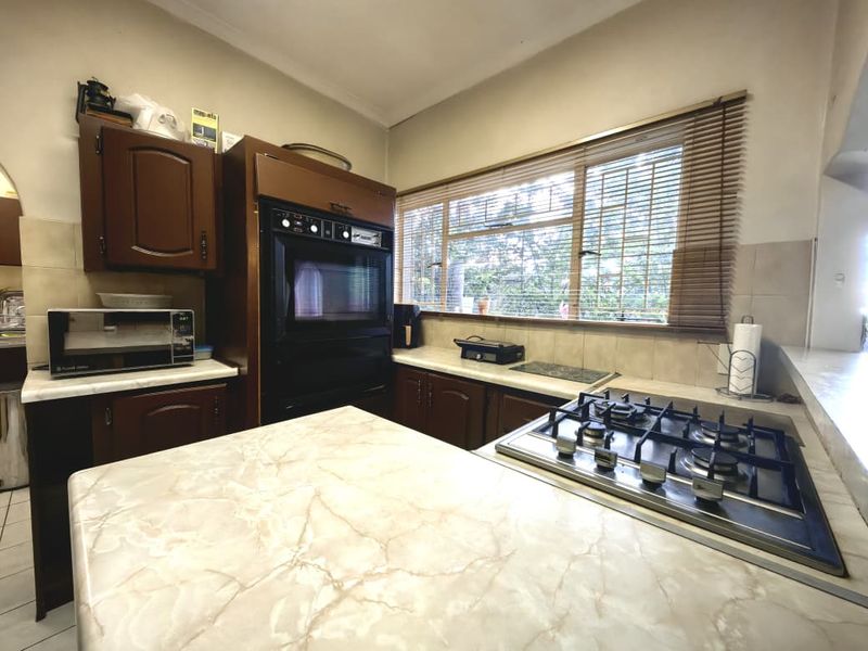 A functional kitchen featuring timber cabinetry, laminate countertops, a built-in oven, and a gas hob with a tiled backsplash.