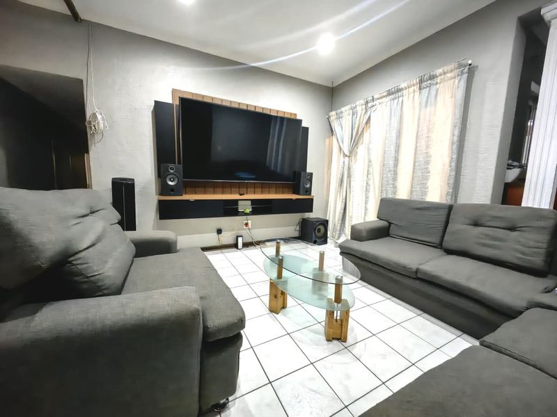 A comfortable living room featuring tiled flooring, recessed lighting, and a custom built-in media console unit.