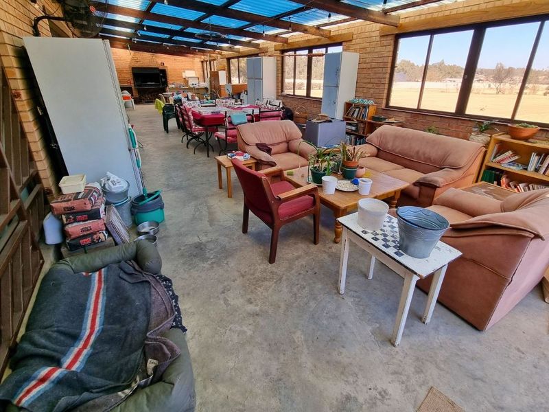 Spacious covered patio featuring exposed brick walls, concrete flooring, and a built-in braai, offering a versatile outdoor entertainment area with expansive views.