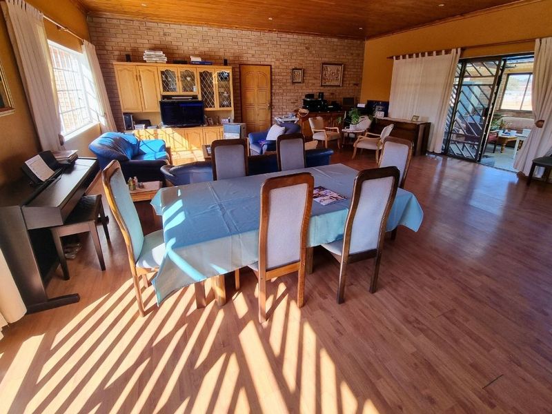 Spacious open-plan living and dining area featuring exposed brick walls, warm timber ceilings, and laminate flooring with direct access to an outdoor patio.