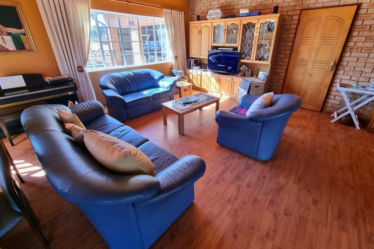 A comfortable living room featuring exposed brick walls, laminate flooring, and large windows that provide ample natural light.