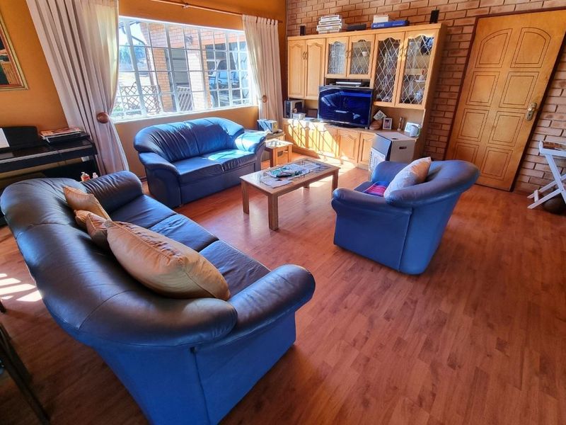 A comfortable living room featuring exposed brick walls, laminate flooring, and large windows that provide ample natural light.