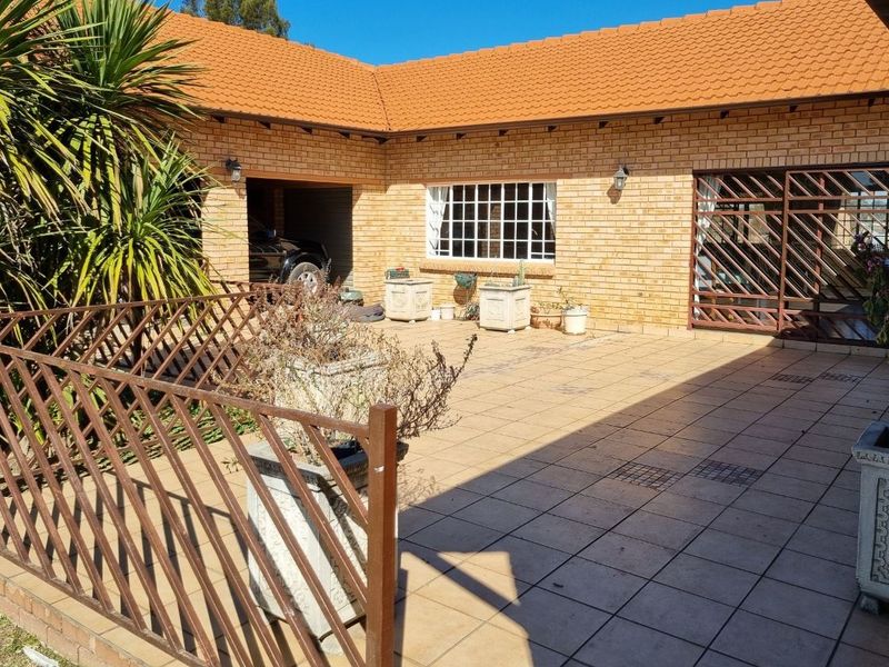A paved outdoor patio area featuring facebrick walls, a tiled roof, and direct access to the garage, providing a functional space for outdoor living.