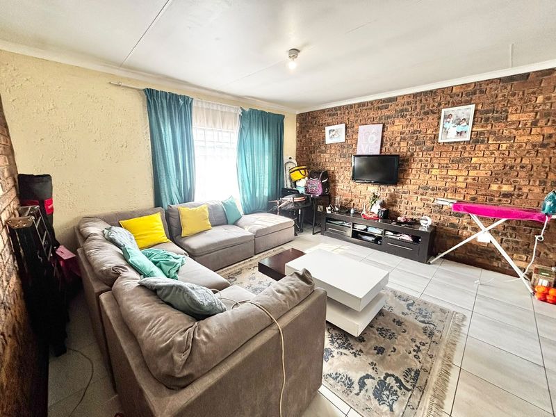 A living room featuring an exposed brick accent wall and tiled flooring, offering a comfortable and characterful space for relaxation.