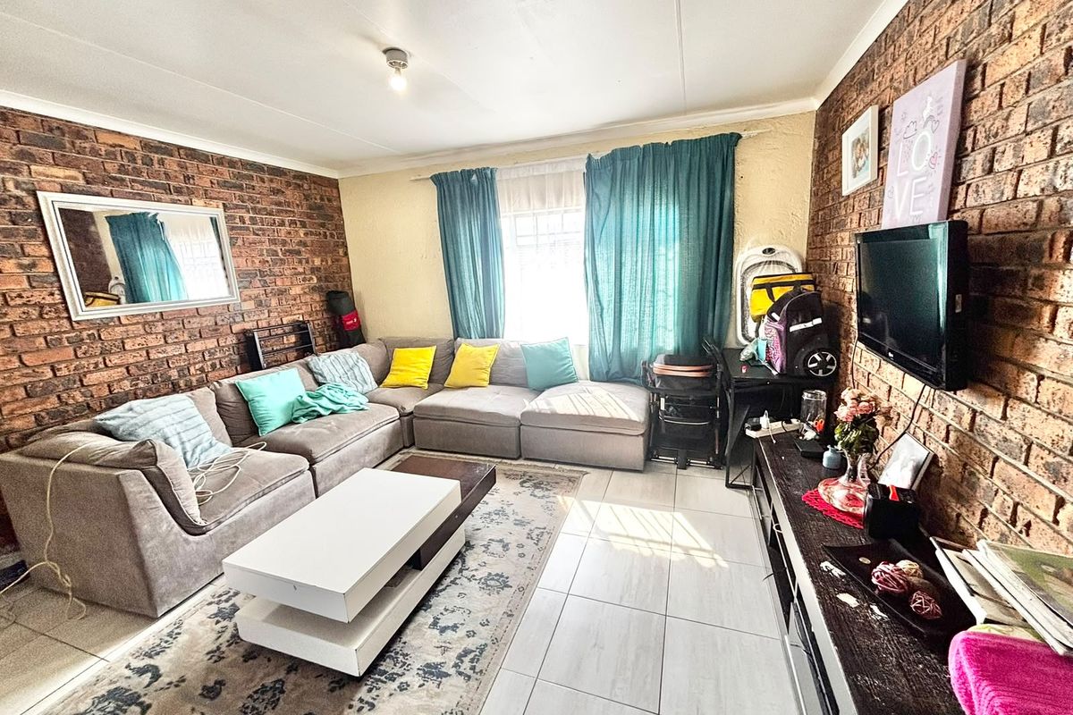 A living room featuring exposed brick feature walls and tiled flooring, providing a textured and character-filled space for relaxation.