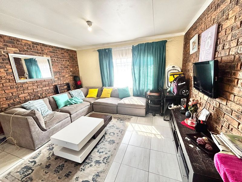 A living room featuring exposed brick feature walls and tiled flooring, providing a textured and character-filled space for relaxation.