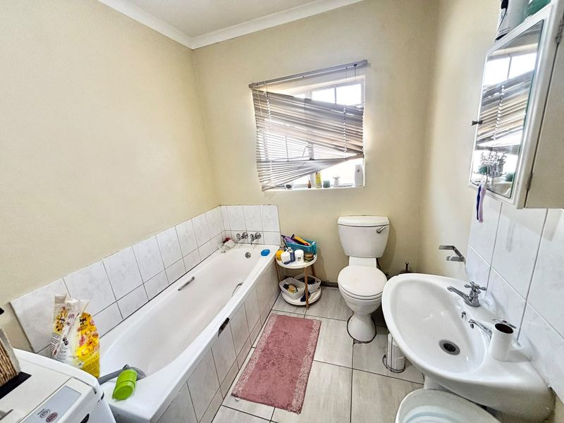 A functional bathroom featuring a bathtub, pedestal basin, and toilet with tiled finishes and a medicine cabinet.