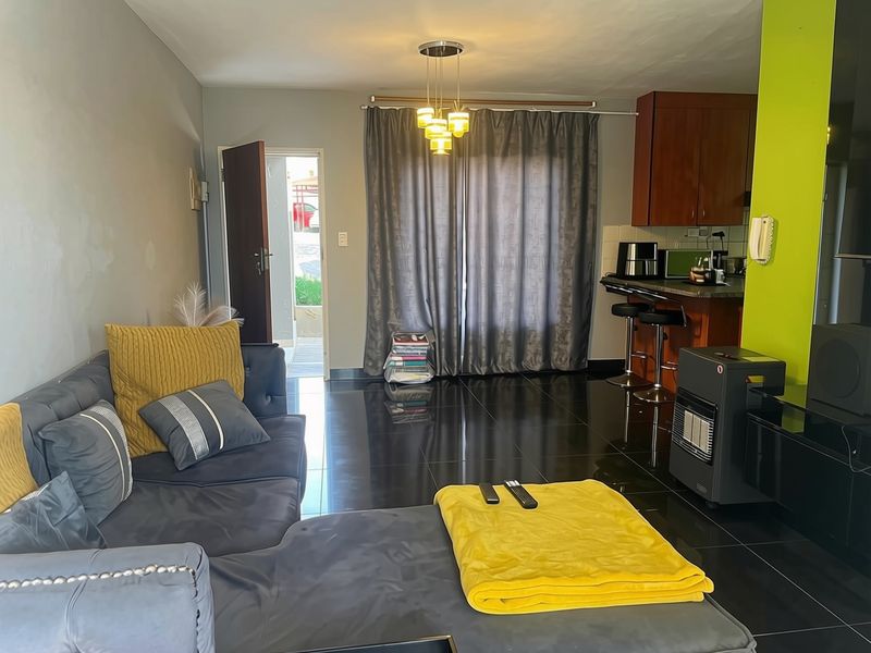Open-plan living area featuring a kitchen with breakfast bar, dark tiled flooring, and direct access to the exterior.