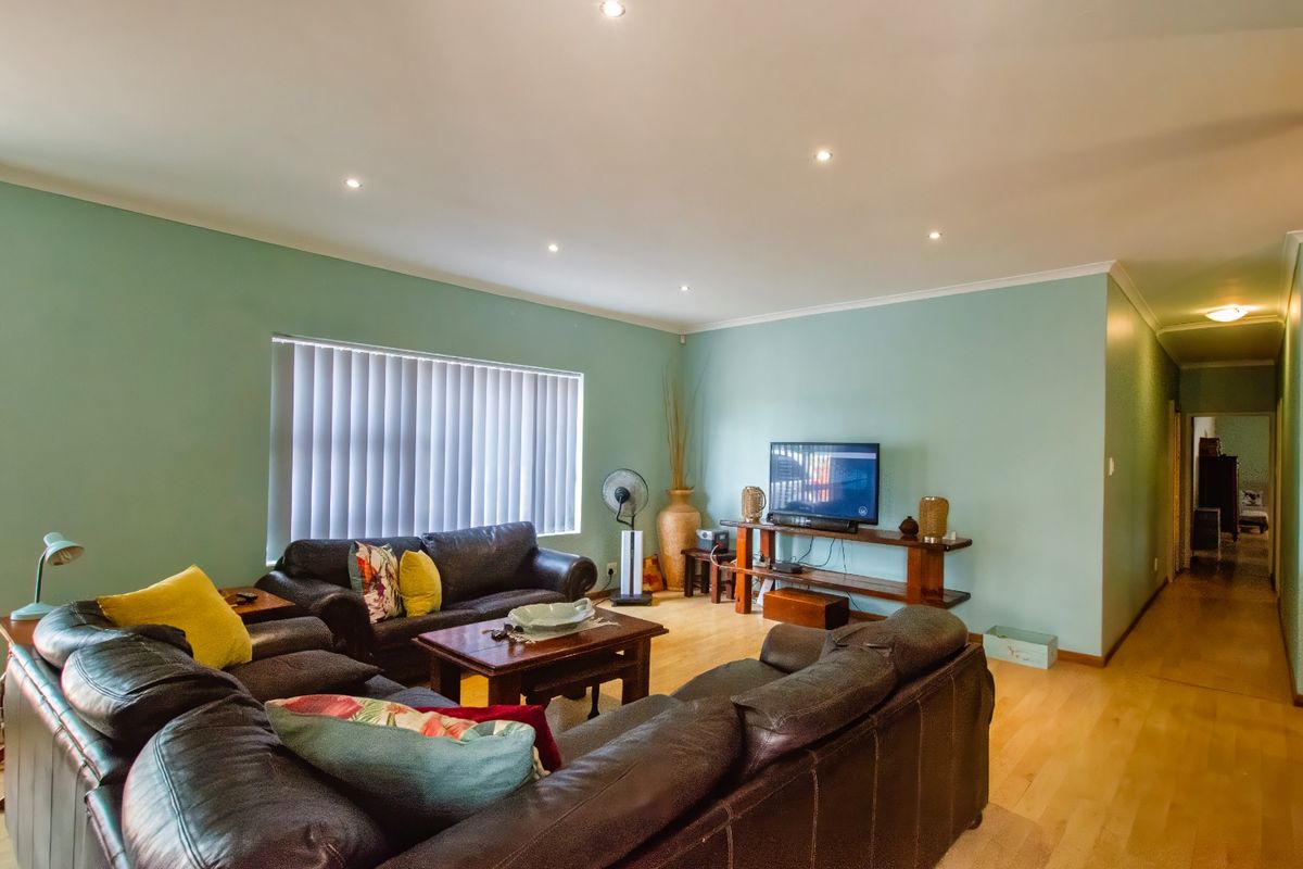 Spacious living room featuring light-toned timber flooring, recessed downlighting, and a neutral color palette, providing a comfortable and functional family living space.