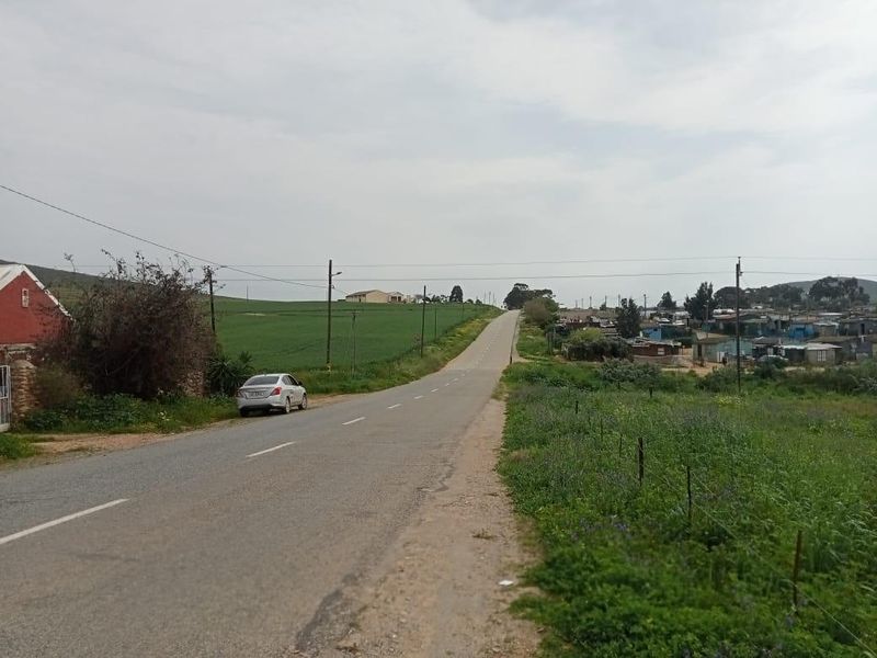 A view of the public road and surrounding landscape, showing the approach to the residential area.