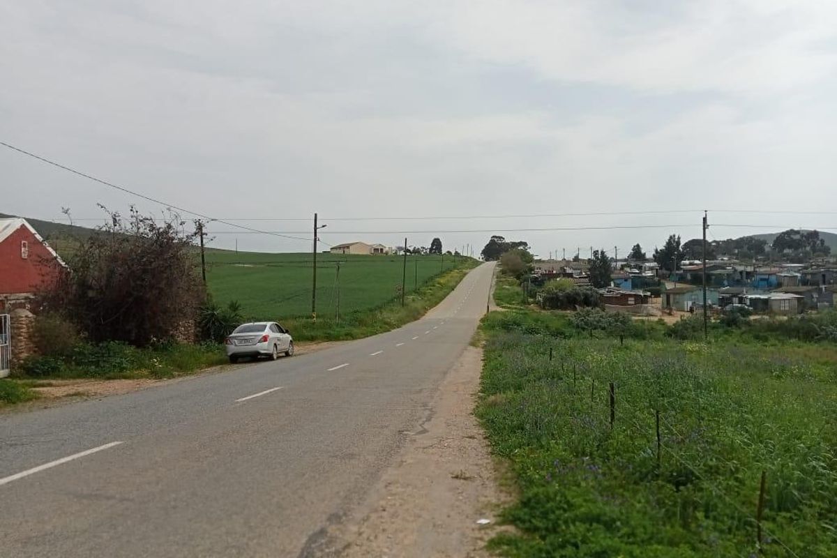 A view of the public road and surrounding landscape, showing the approach to the residential area.