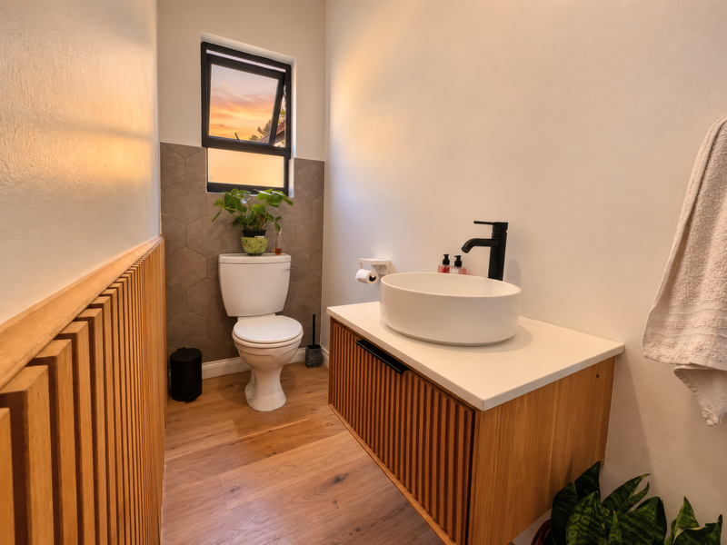 Modern guest bathroom featuring a floating timber vanity, vessel sink with black fixtures, and stylish timber slat wall paneling.