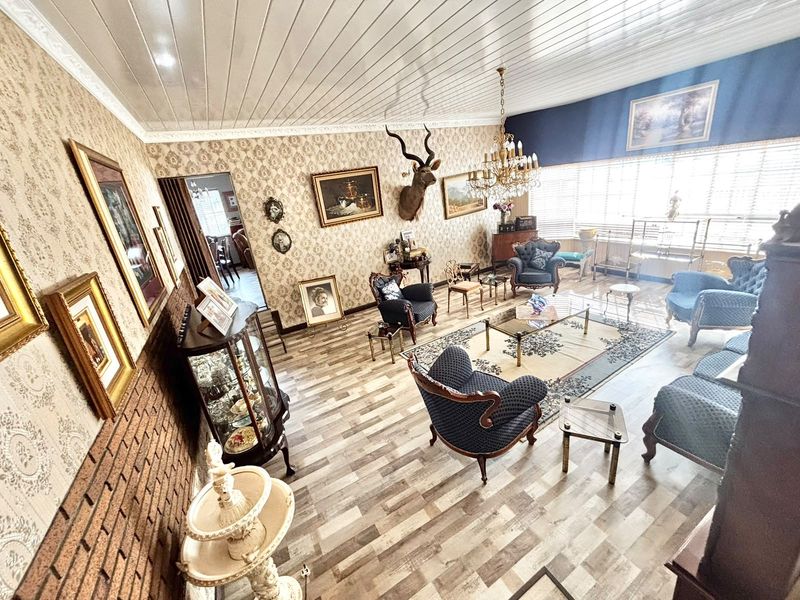 Spacious living room featuring exposed brick accents, patterned wallpaper, wood-look flooring, and a classic crystal chandelier.