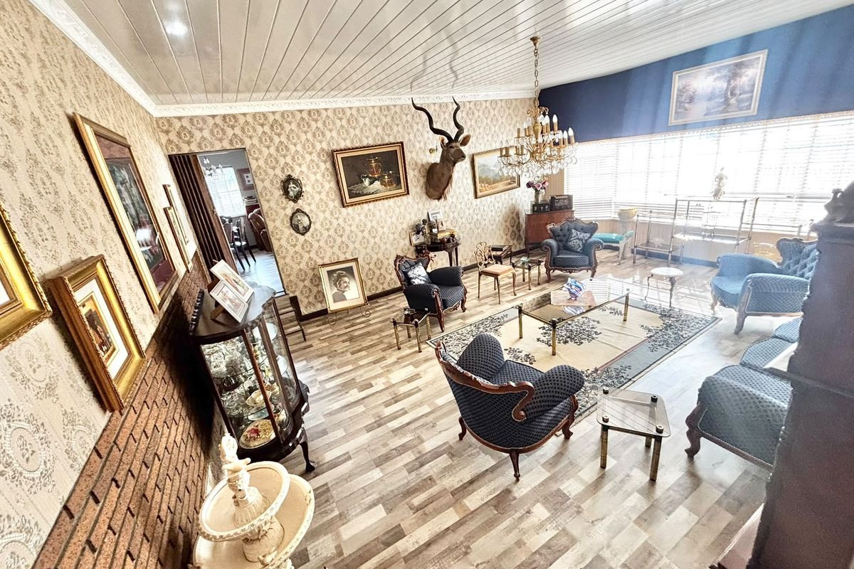 Spacious living room featuring exposed brick accents, patterned wallpaper, wood-look flooring, and a classic crystal chandelier.