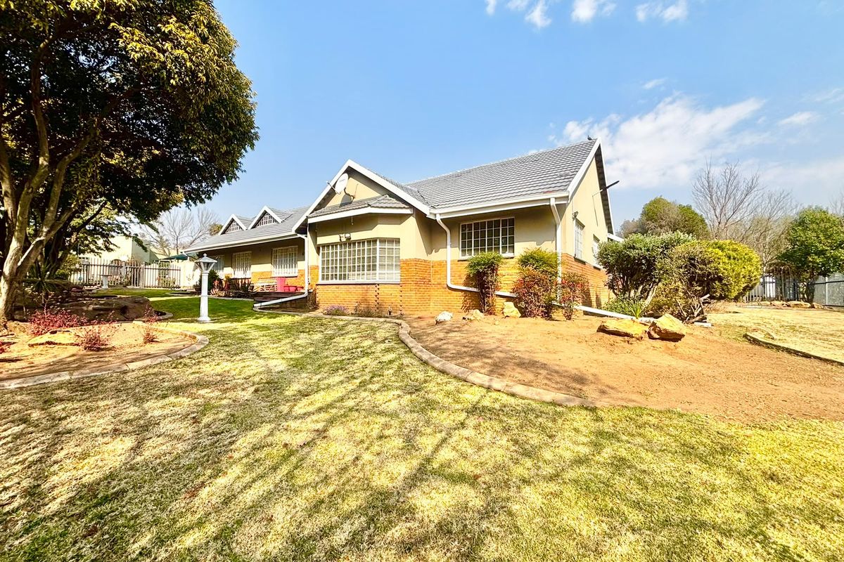 A well-maintained single-story residential home featuring a brick and plaster facade, tiled roof, and established garden surroundings.