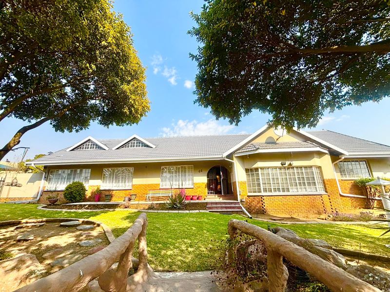 A well-maintained single-story residential property featuring a tiled roof, brick facade, and established garden with mature trees.