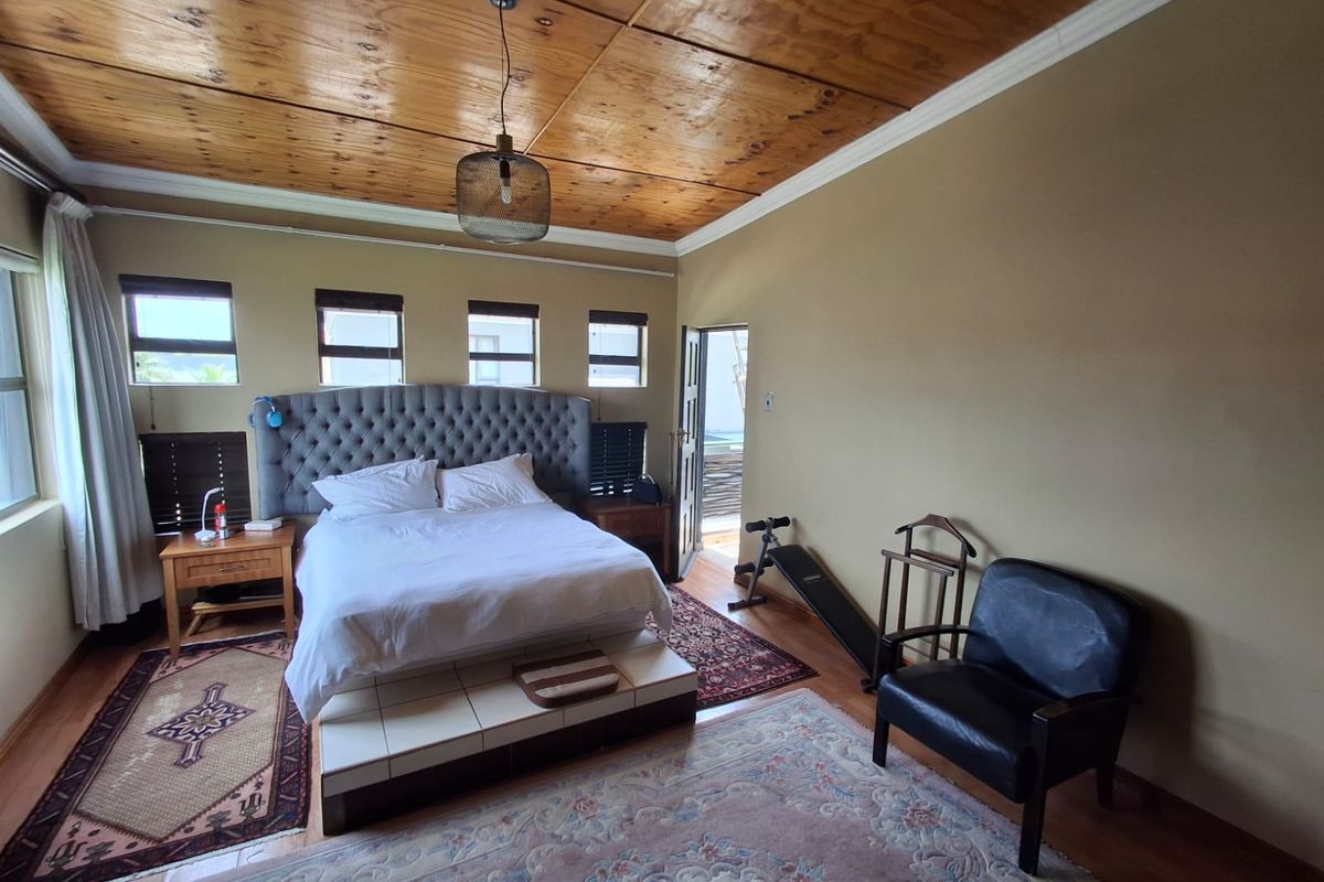 Spacious bedroom featuring a unique timber ceiling, tiled bed base, and direct access to an outdoor area through a side door.