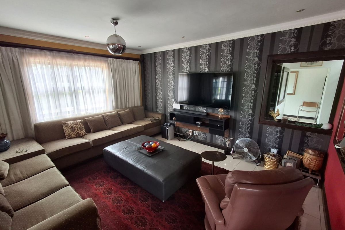 A comfortable living room featuring tiled flooring, decorative wallpaper, and a built-in media console, offering a functional space for relaxation.